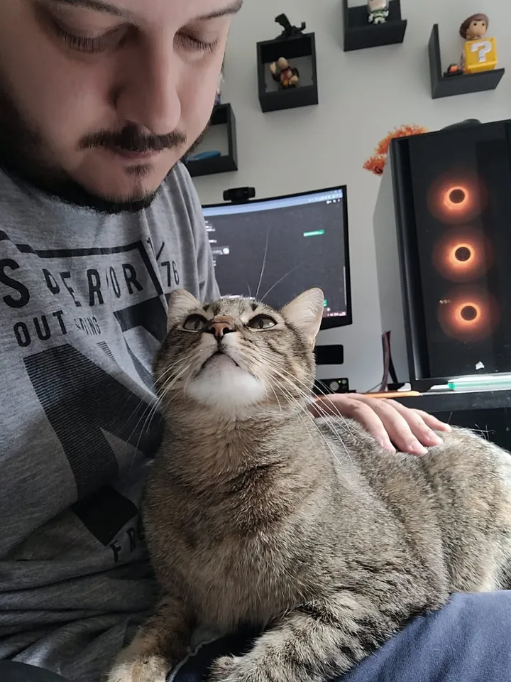 Breno at his desk with Melissa, his cat, on his lap
